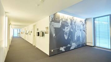 Un couloir orné d’une grande fresque murale, avec un panneau portant le chiffre « 5 » et une fenêtre avec des stores.