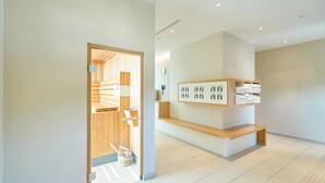 Un vestíbul d'hotel modern amb una taulell de recepció de fusta, un suport de tovalloles fixat a la paret i un rellotge a la vista.