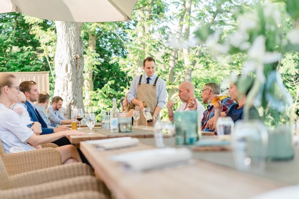 An outdoor dining area with wicker furniture and tables set for a group meal.