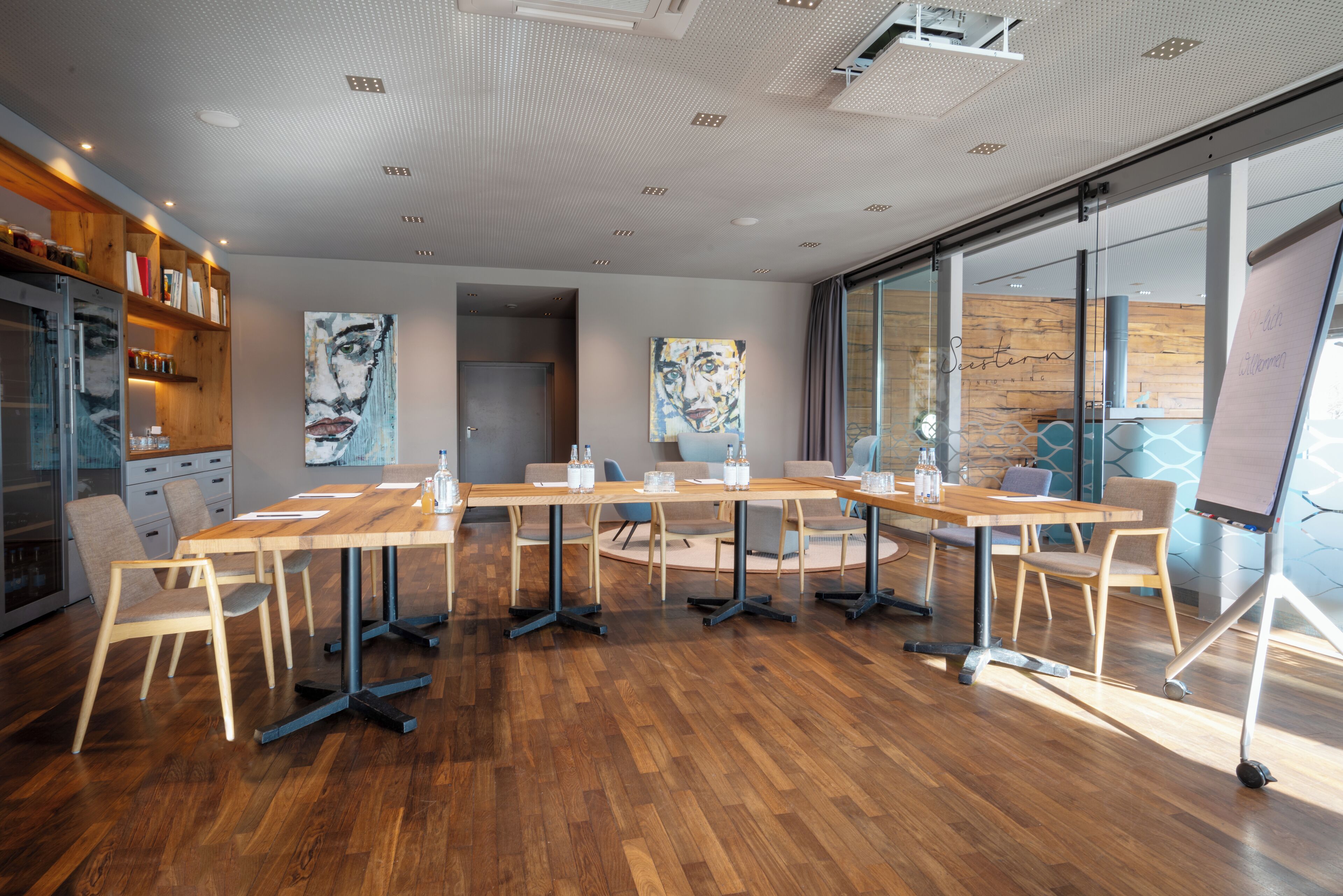 A modern conference room with a wooden table, chairs, and artwork on the walls.