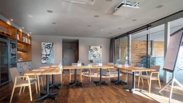 A modern conference room with a wooden table, chairs, and artwork on the walls.