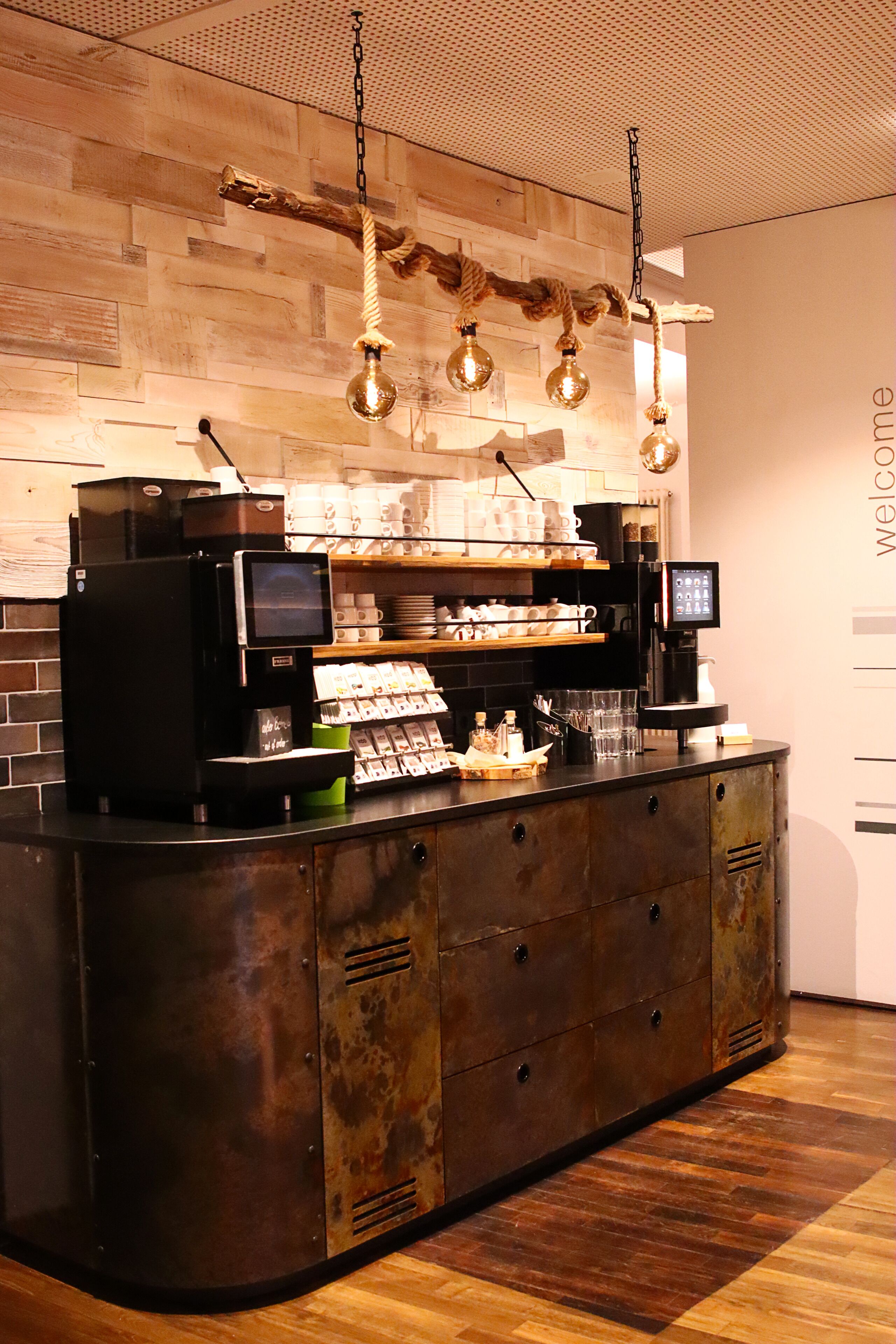 A coffee shop with a rustic wooden counter, a coffee machine, and a display of coffee cups.