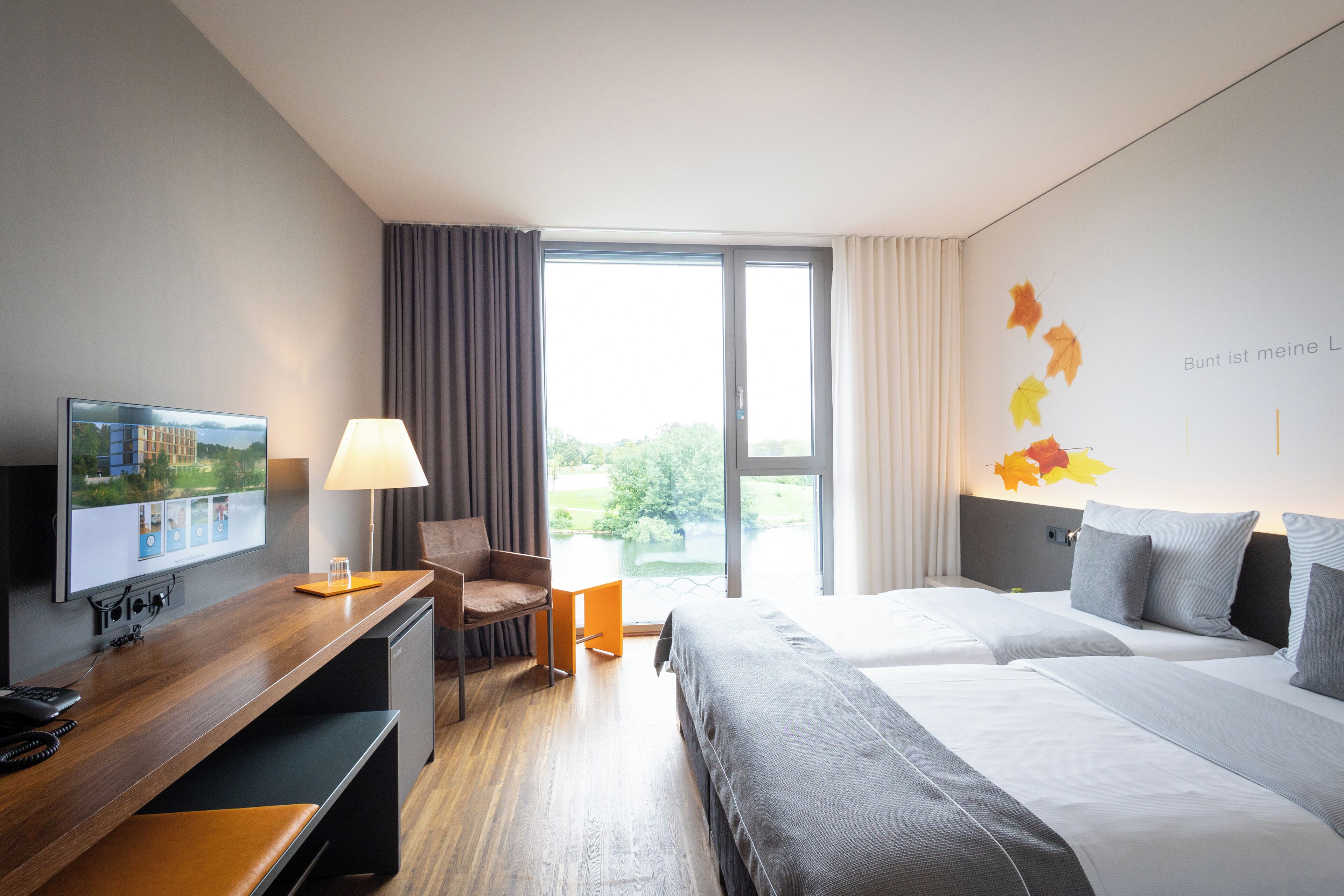 A hotel room with a bed, a desk with a computer, a chair, and a TV.
