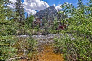 A mountain lodge with a river in front, surrounded by trees and a clear sky. - Ten Mile Island 119c 2 Bedroom Condo by RedAwning (Frisco)