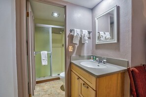A bathroom with a shower, toilet, sink, and two mirrors.