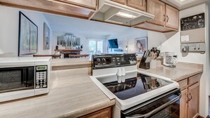 A modern kitchen with wooden cabinets, a microwave, stove, and a coffee maker. - Mountainside 229e 1 Bedroom Condo by RedAwning (Frisco)