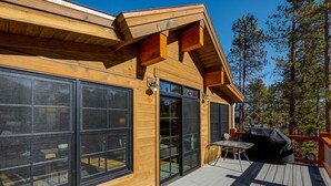 Een houten chalet met grote ramen, een terras en buitenzitplaatsen.