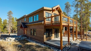 Een modern houten huis met een balkon, grote ramen en een stenen fundering.