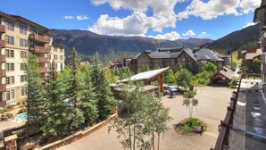A hotel with multiple floors, a pool, and a mountainous backdrop.