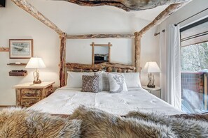 A bedroom with a rustic design, featuring a bed with a wooden headboard, two bedside tables with lamps, and a large mirror above the bed. - Lagoon  762b 3 Bedroom Townhouse by RedAwning (Frisco)