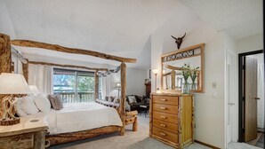 Une chambre à coucher rustique avec un lit à baldaquin, une commode en bois et un grand miroir orné d’une tête de taureau.