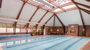 Une piscine intérieure avec un plafond haut et des murs en briques.
