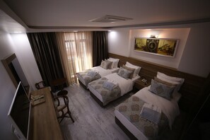 A hotel room with two beds, a desk, a chair, a TV, and a painting on the wall. - Grand Serenay Hotel (Bandirma)
