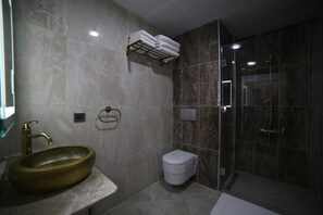 A bathroom with a marble sink, a toilet, and a glass-enclosed shower. - Grand Serenay Hotel (Bandirma)