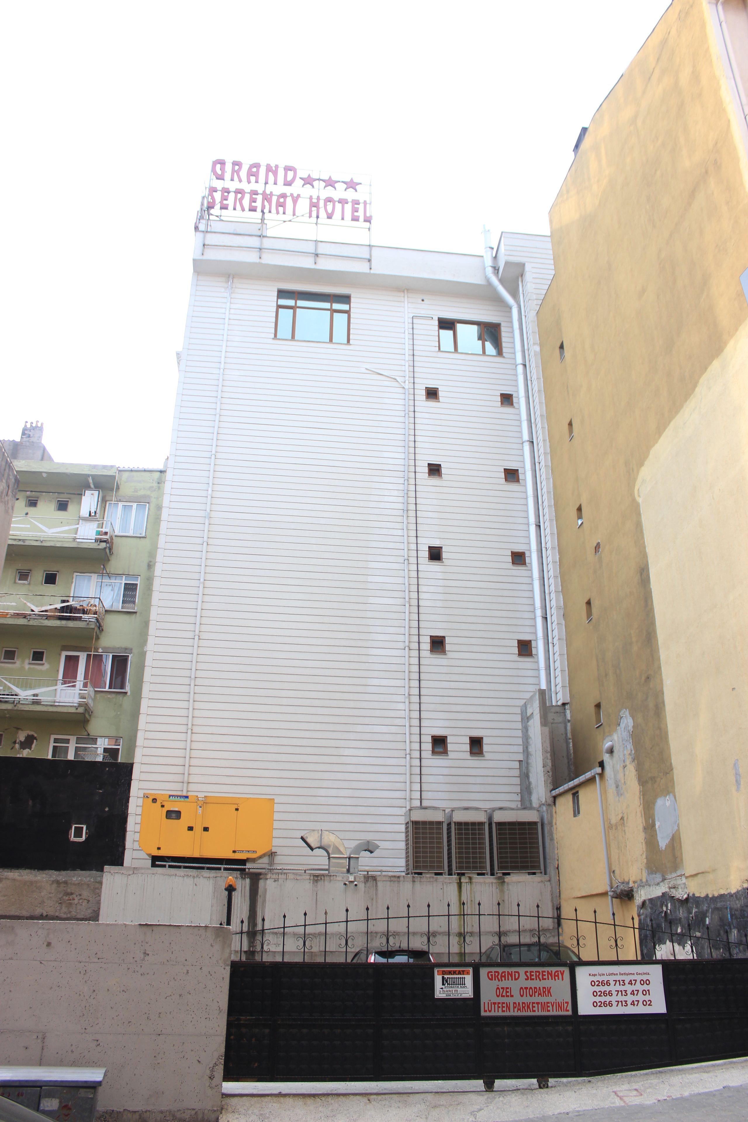 A multi-story hotel building with a sign reading "Grand Serenity Hotel".