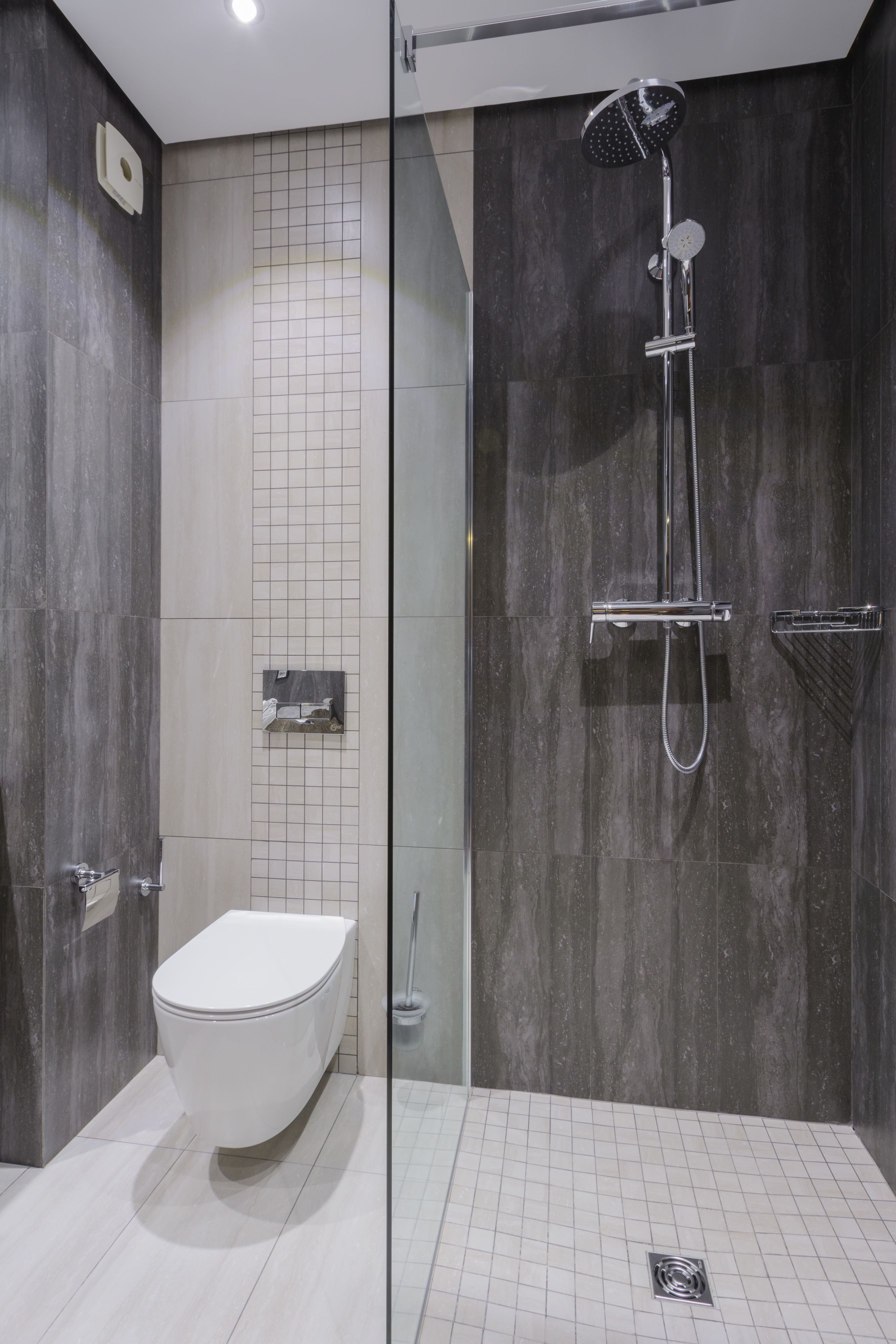 Un baño moderno con ducha de vidrio, inodoro blanco y piso de baldosas.