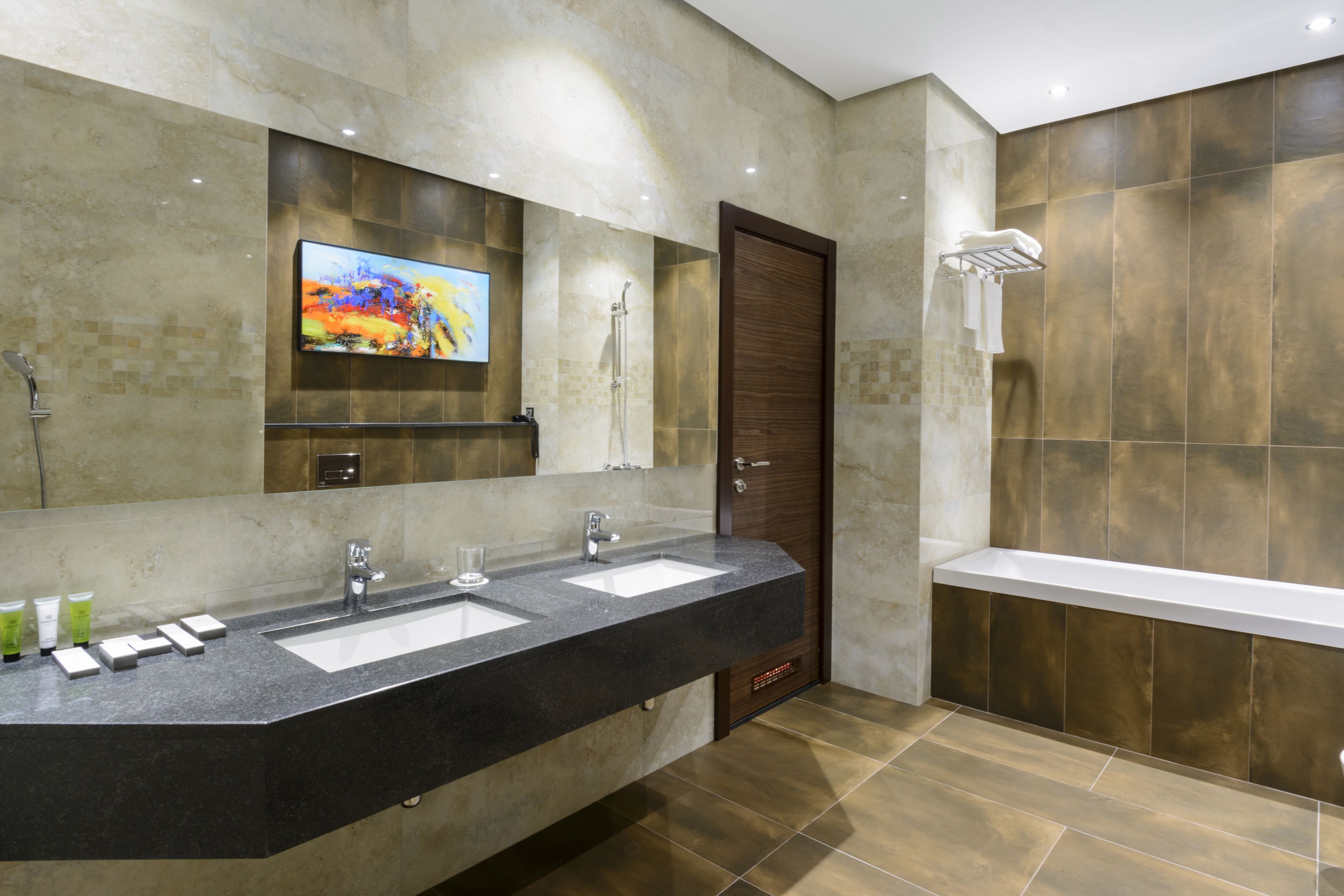 A modern bathroom with two sinks, a large mirror, a shower, and a toilet.