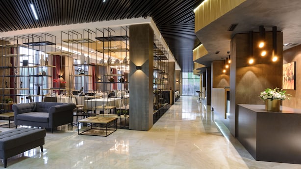 Un hall d’entrée spacieux avec un plafond haut, un mobilier moderne et un comptoir d’accueil.