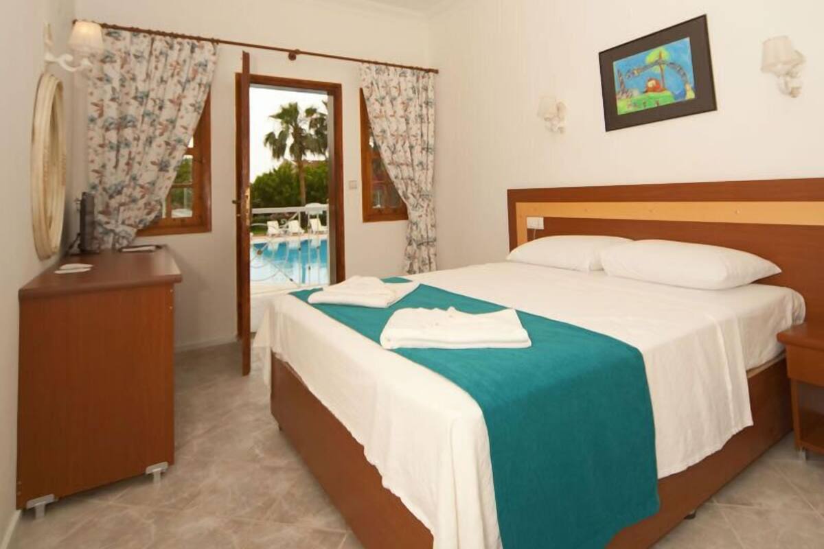Habitación de hotel con cama, escritorio y vistas a una piscina.