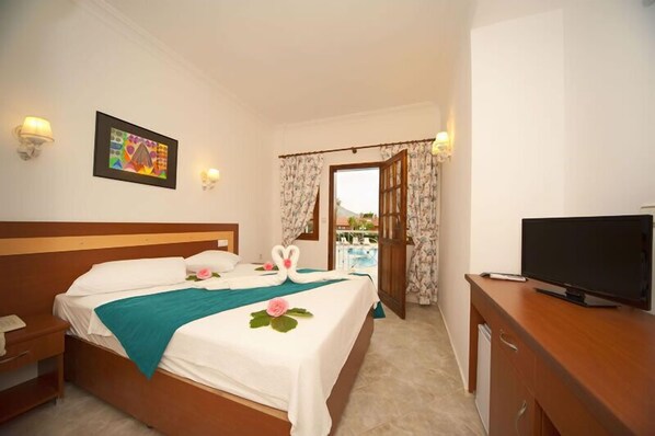 A hotel room with a bed, a TV, a desk, and a window with curtains. - White Hotel (Fethiye)