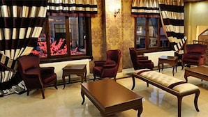 Un salon spacieux doté d’une cheminée, de sièges confortables et d’une grande fenêtre agrémentée de rideaux.