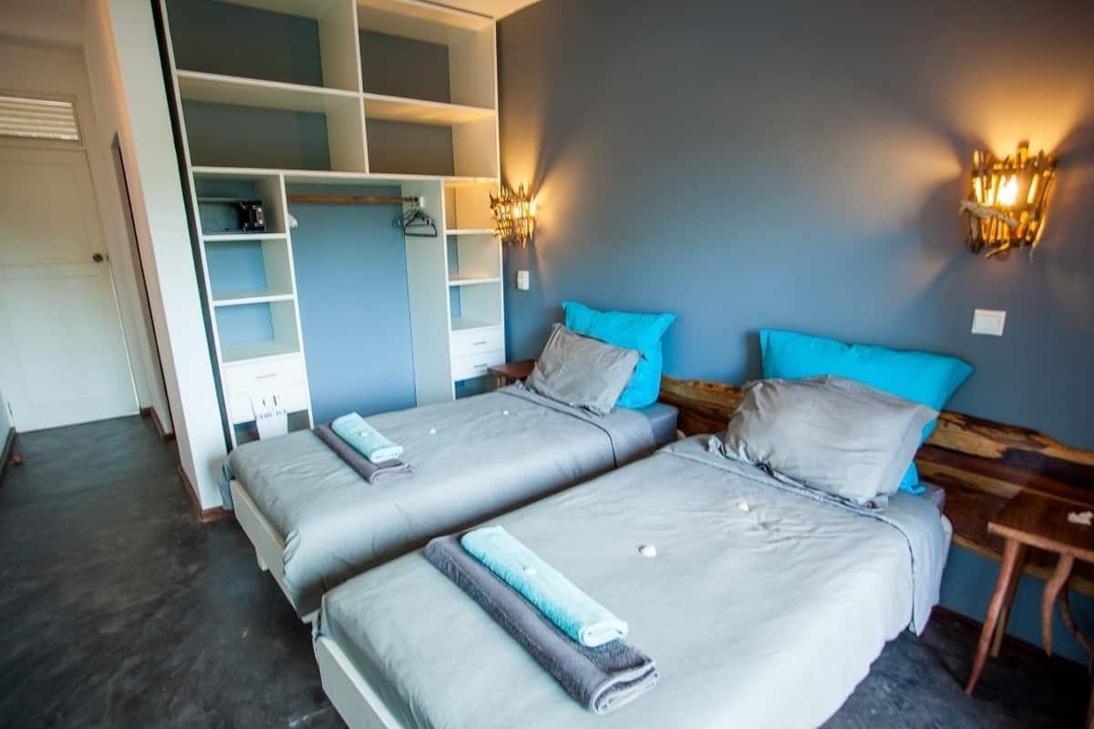 A bedroom with two beds, a wardrobe, and a nightstand with a lamp.