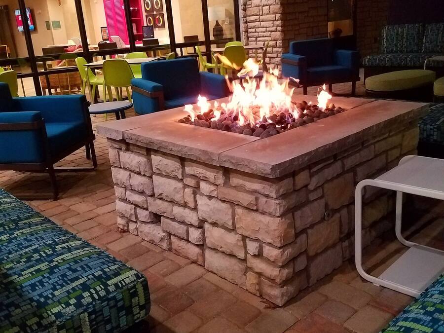 A stone fire pit surrounded by outdoor seating with a brick floor.