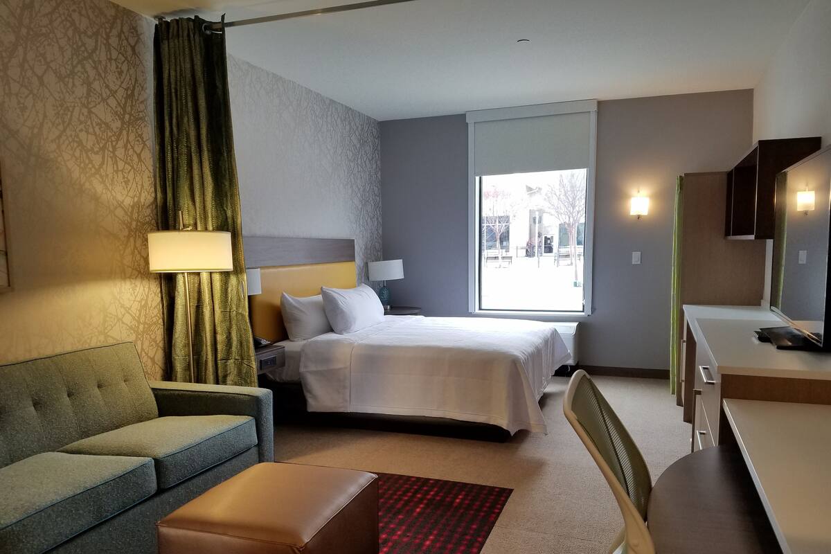 A hotel room with a bed, a sofa, a desk, and a chair.