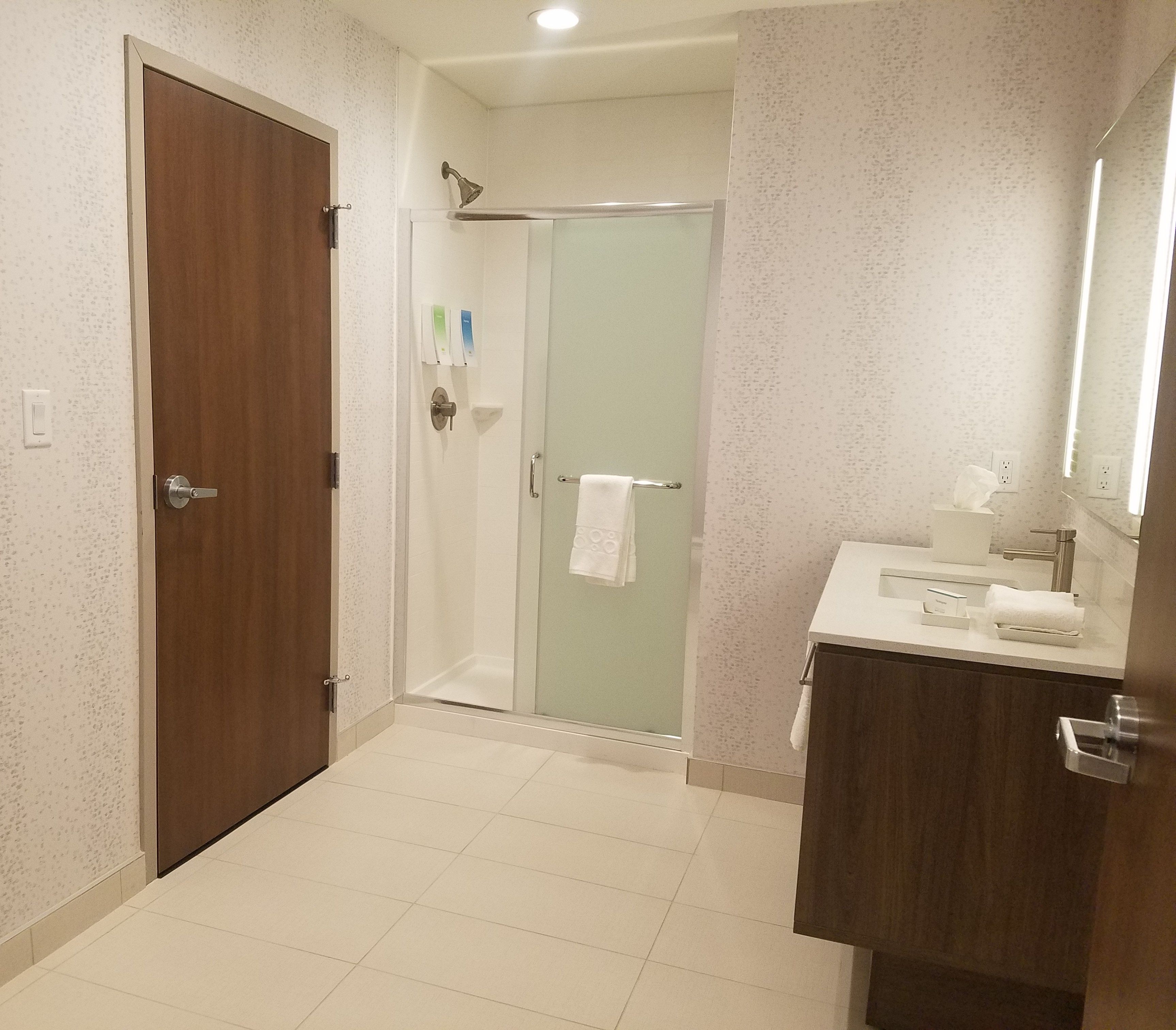 Un baño con ducha, lavamanos y espejo.