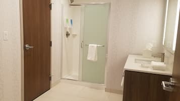 Un baño con ducha, lavamanos y espejo.