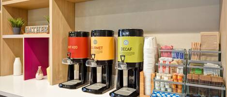 En kaffestation med tre kaffedispensrar märkta med "VARMT VATTEN", "LYXKAFFE" och "KAFFE UTAN KOFFEIN".