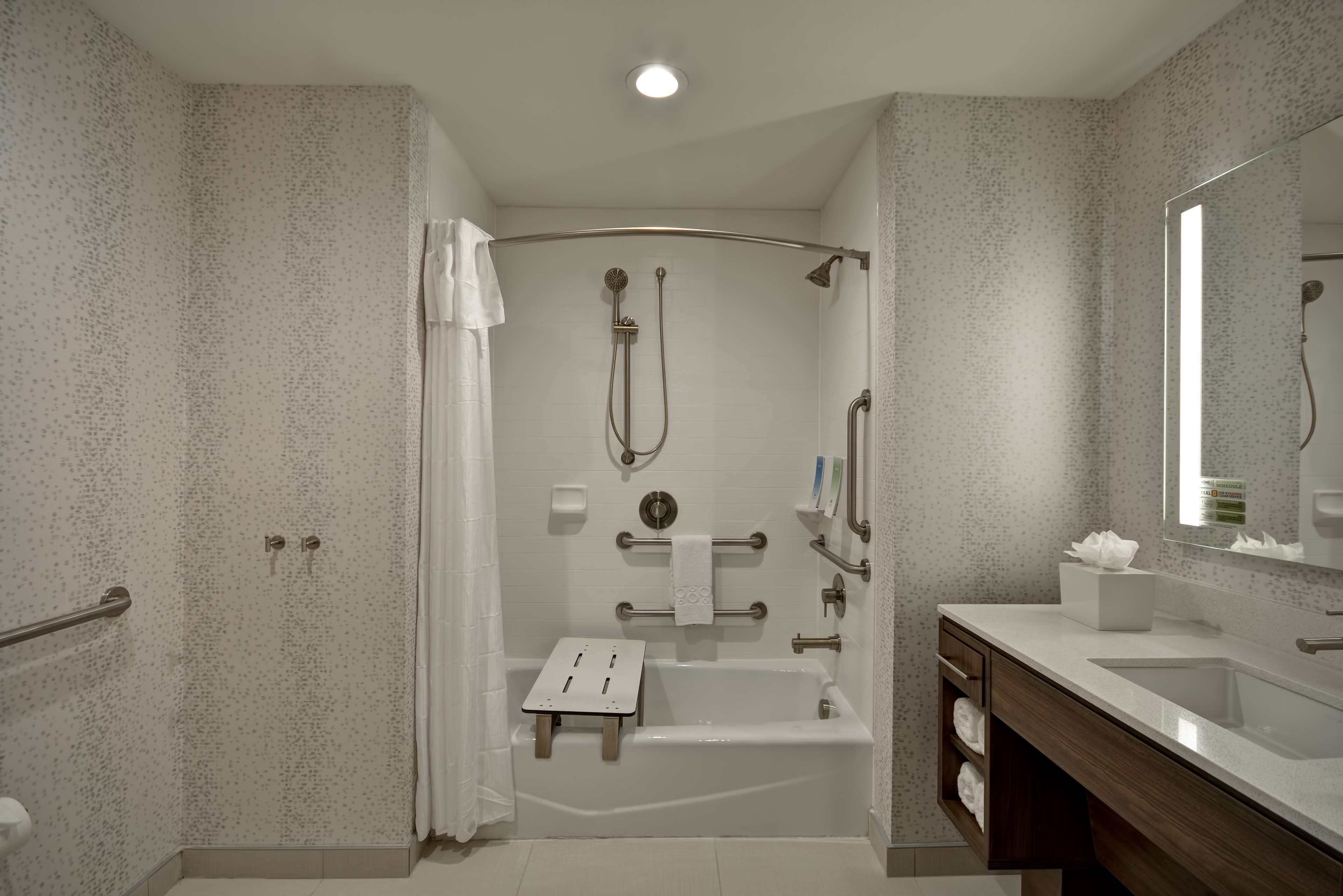 A modern bathroom with a bathtub, shower, and a vanity with a sink.