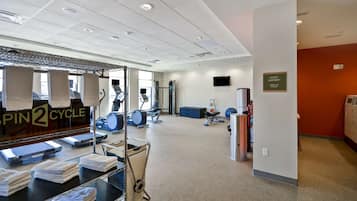 A gym with exercise equipment, a guest laundry sign, and a wall-mounted television.