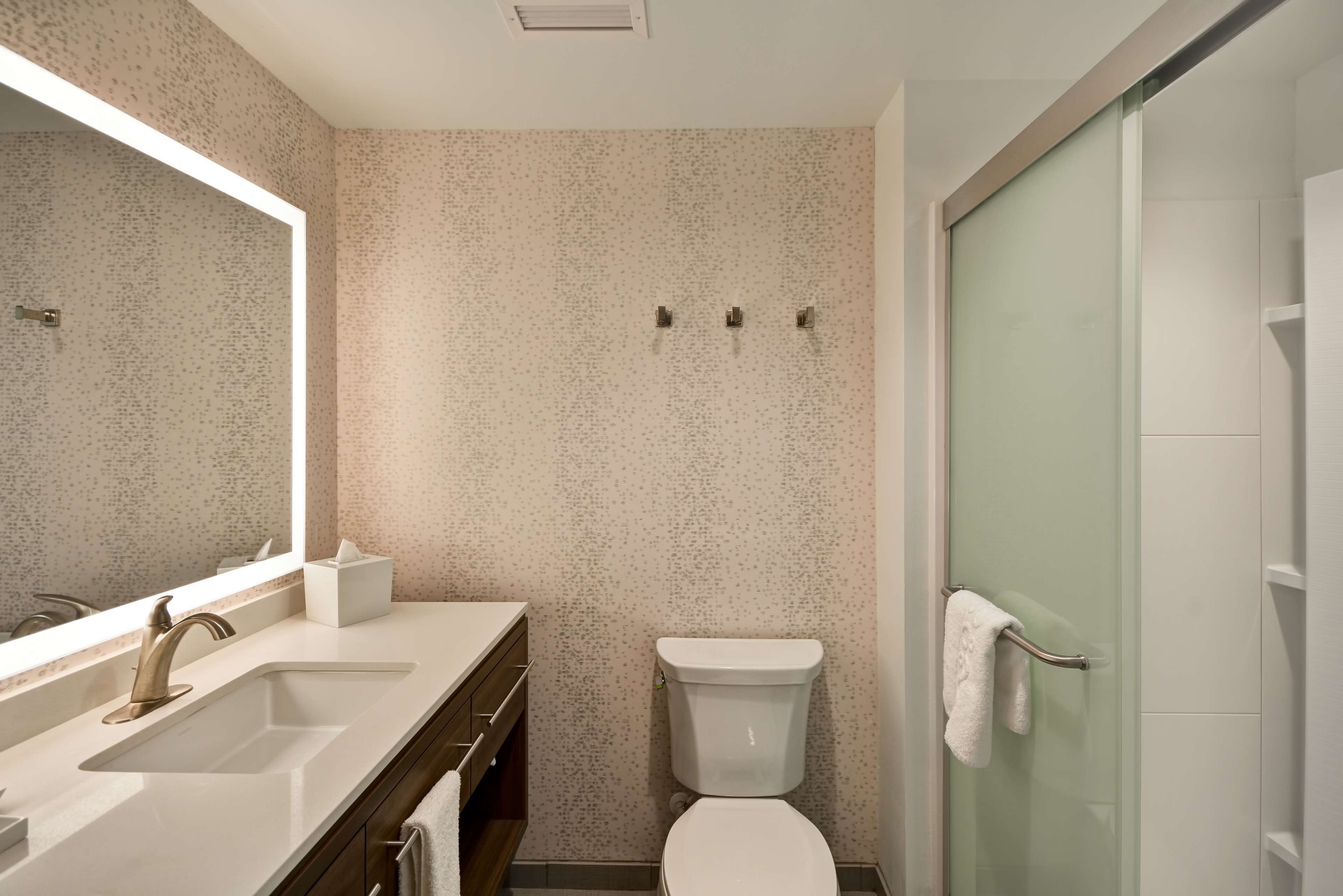 Een moderne badkamer met een grote spiegel, een wastafel, een toilet en een douchecabine met glazen wanden.