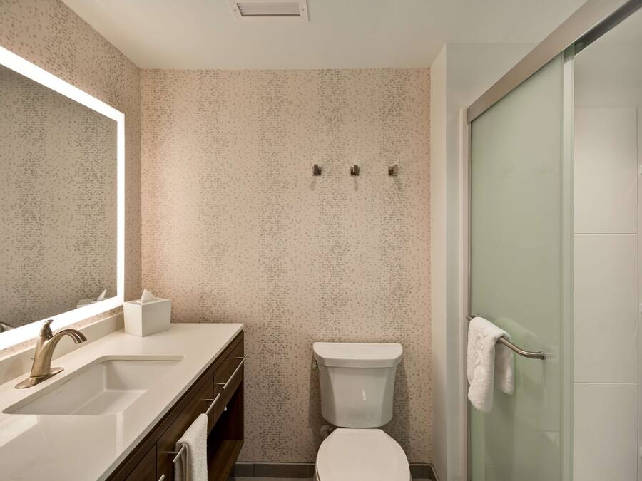 Een moderne badkamer met een grote spiegel, een wastafel, een toilet en een douchecabine met glazen wanden.