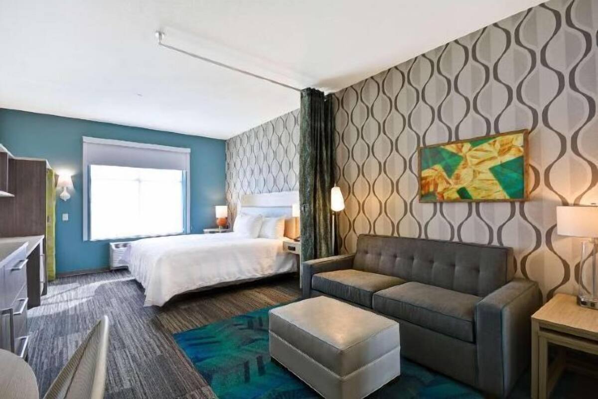 Una habitación de hotel con una cama, un sofá, un escritorio, una silla y una ventana.