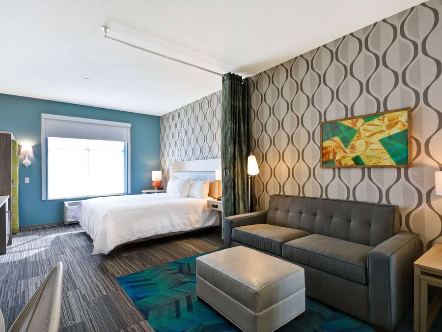 Ett hotellrum med en säng, en soffa, ett skrivbord och en stol.
