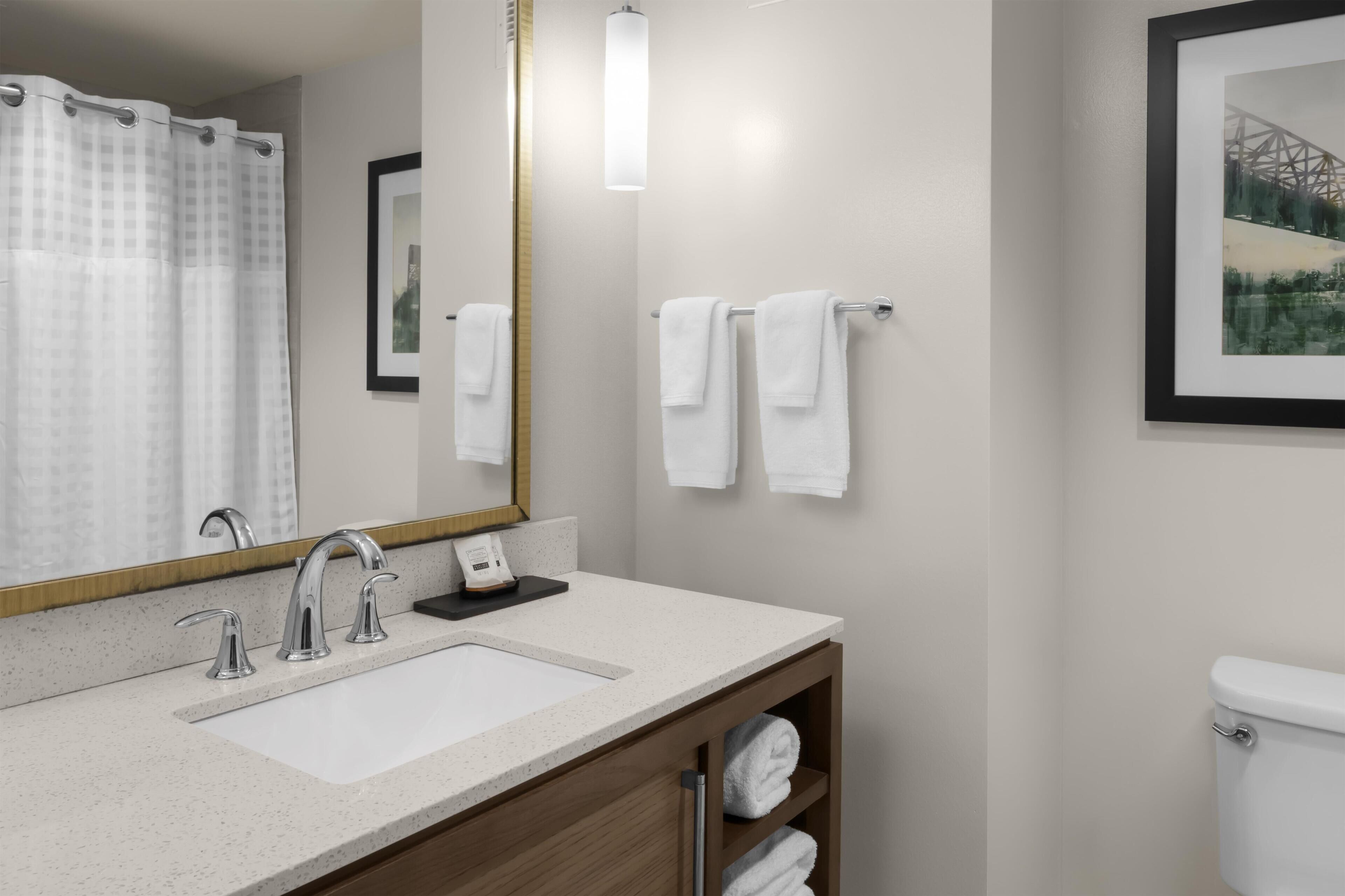 A bathroom with a white sink, a mirror, a towel rack, and a toilet.