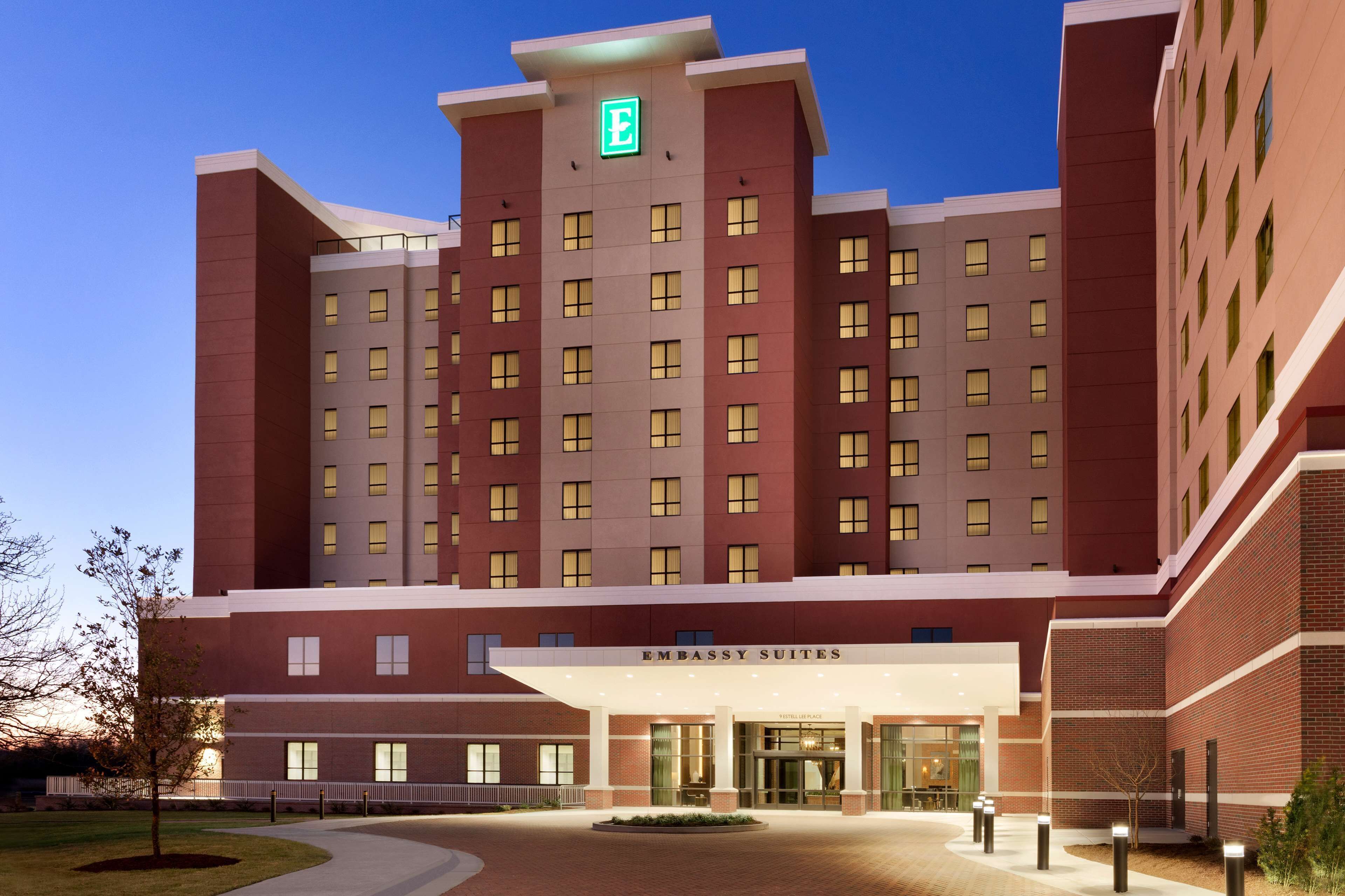 A multi-story hotel with a prominent entrance, a green emergency exit sign, and a sign indicating "Embassy Suites."
