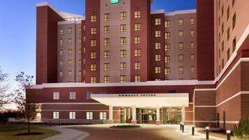 A multi-story hotel with a prominent entrance, a green emergency exit sign, and a sign indicating "Embassy Suites."