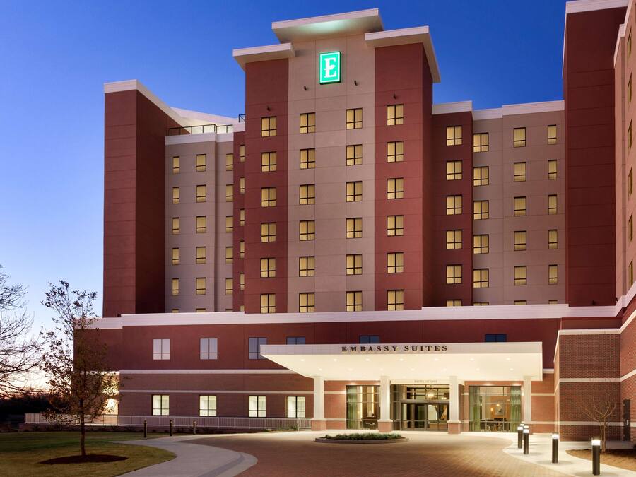 A multi-story hotel with a prominent entrance, a green emergency exit sign, and a sign indicating "Embassy Suites."
