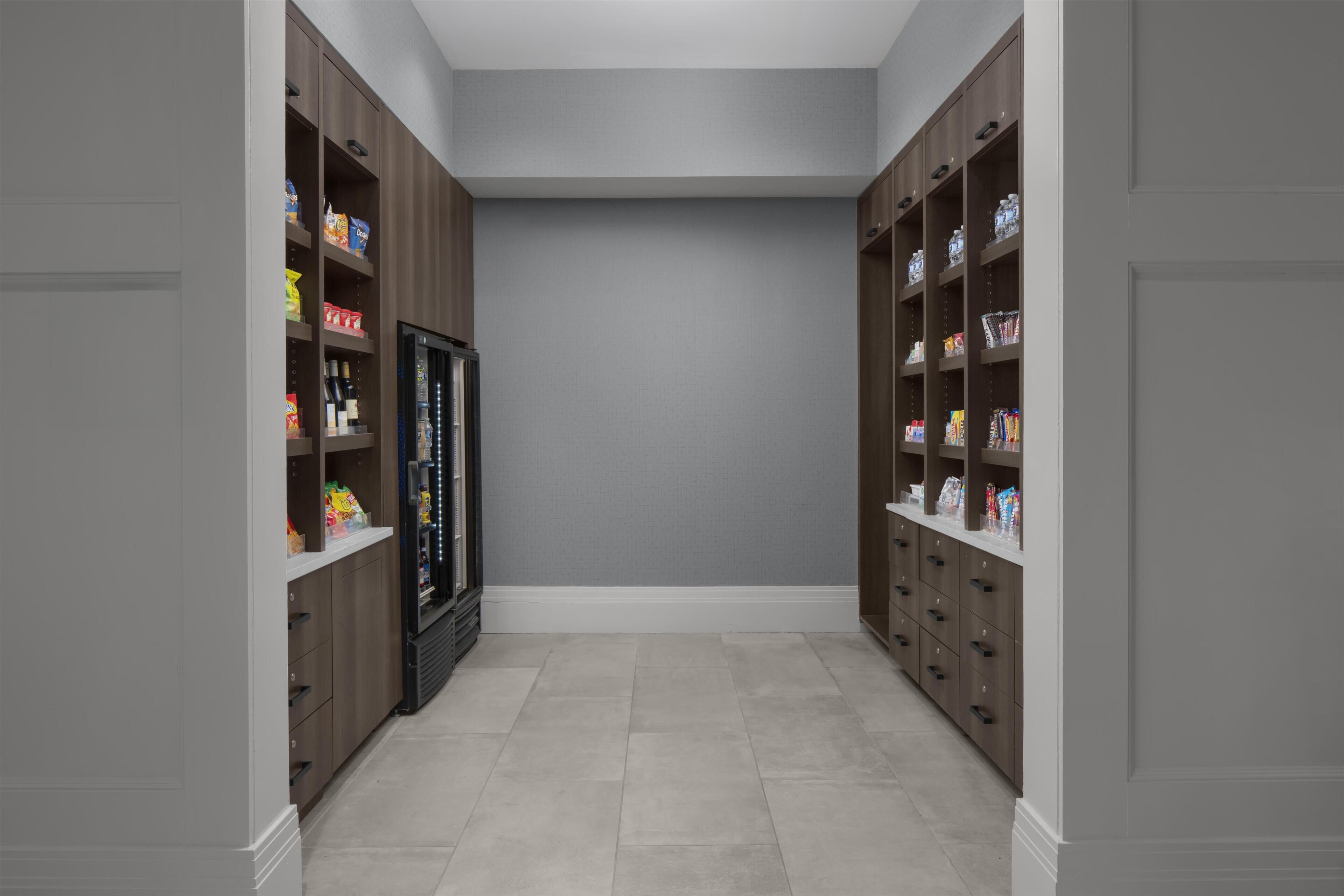 A narrow hallway with wooden cabinets on either side, containing various food items and beverages.