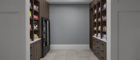 A narrow hallway with wooden cabinets on either side, containing various food items and beverages.