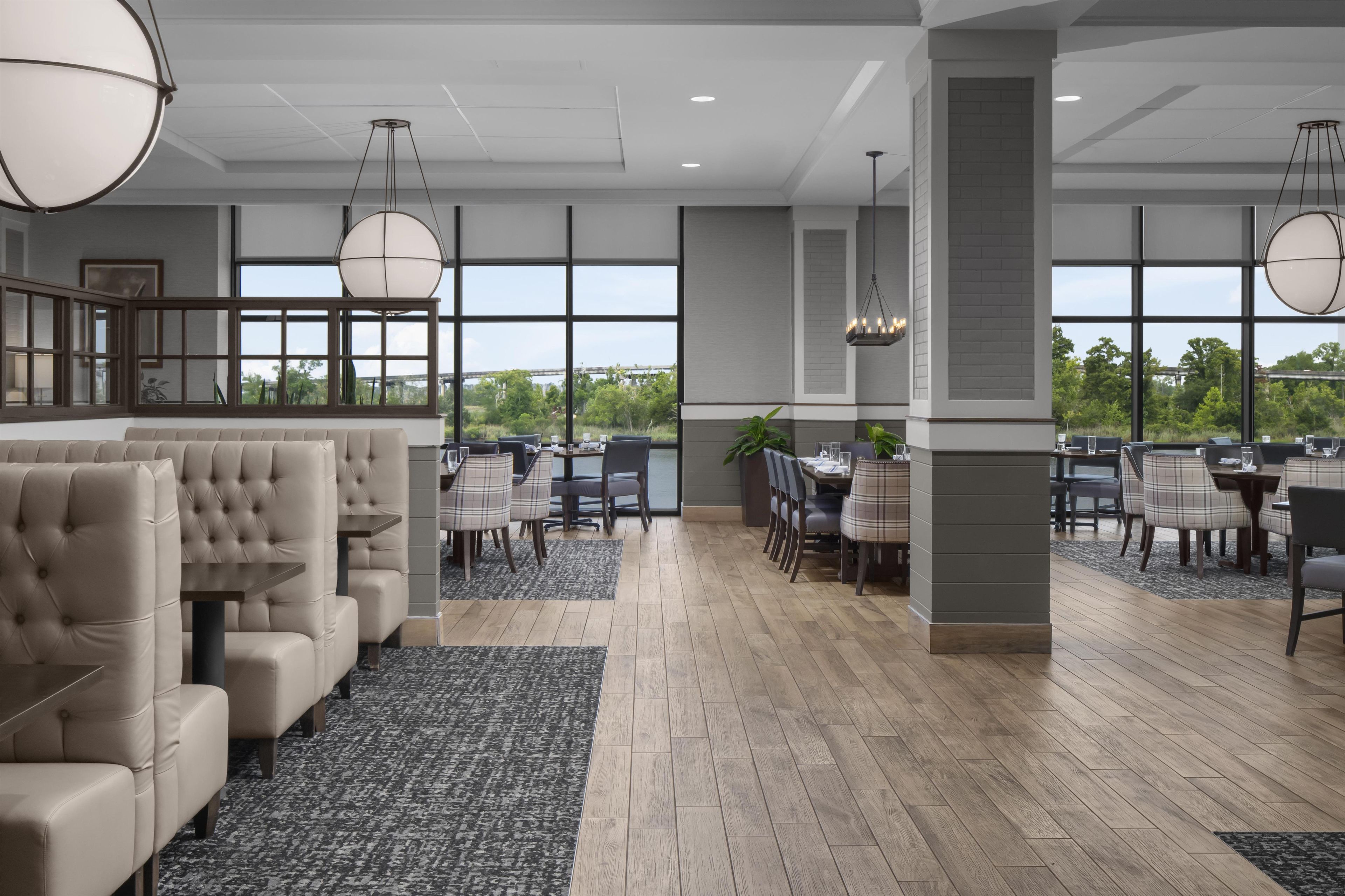 A spacious indoor area with a seating arrangement, large windows, and a view of greenery outside.