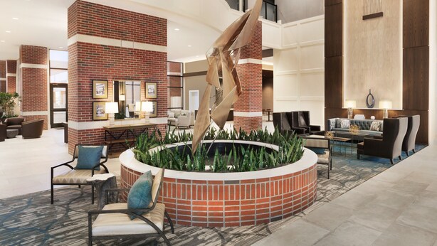 A spacious lobby with a reception desk, seating area, and a central decorative feature. - Embassy Suites by Hilton Wilmington Riverfront (Wilmington)
