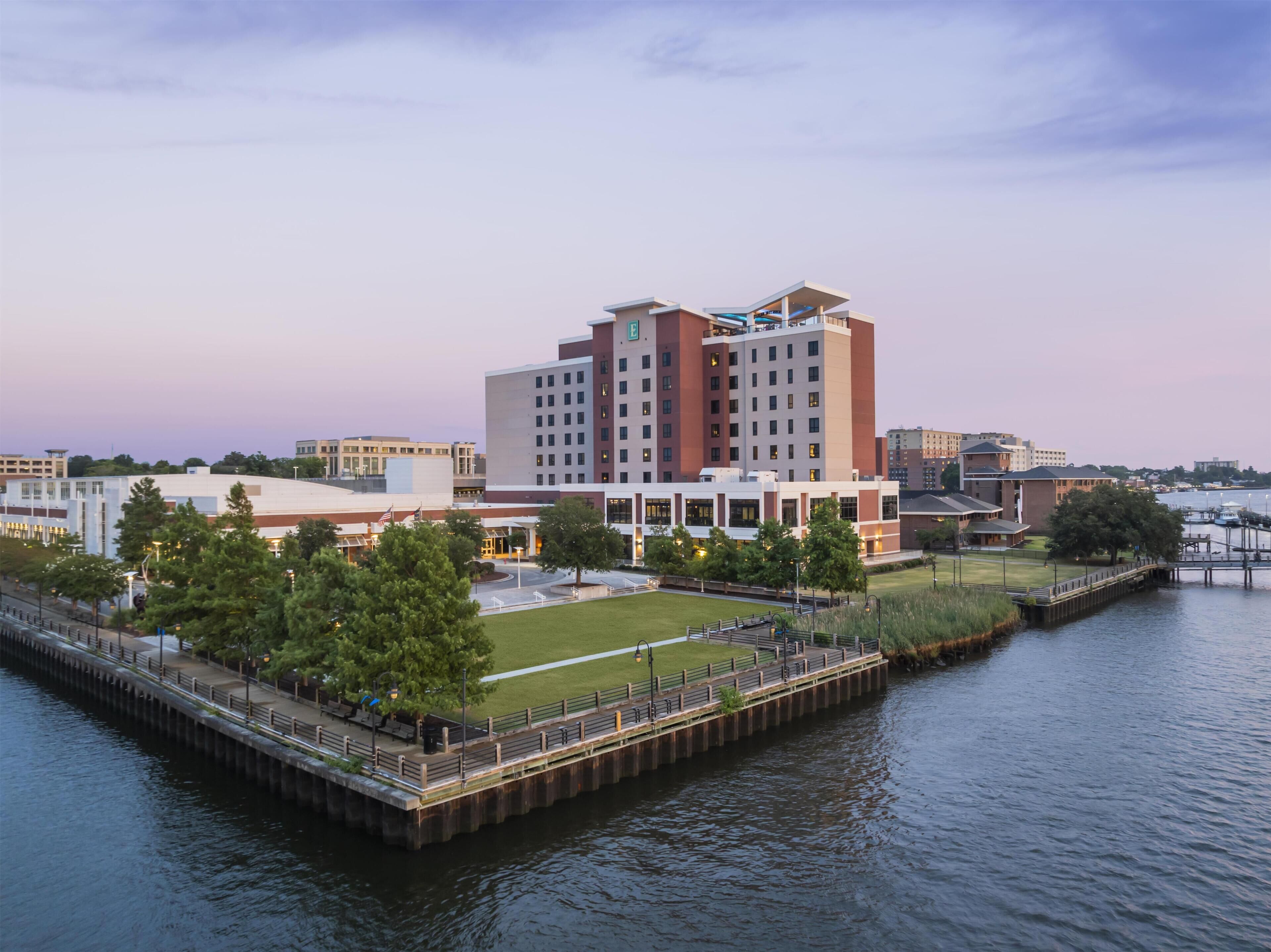 A waterfront hotel with a dock, a grassy area, and a parking lot.