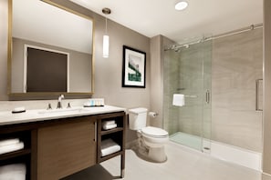 Een moderne badkamer met een grote spiegel, een wastafel, toilet en een douchecabine met glazen wanden.