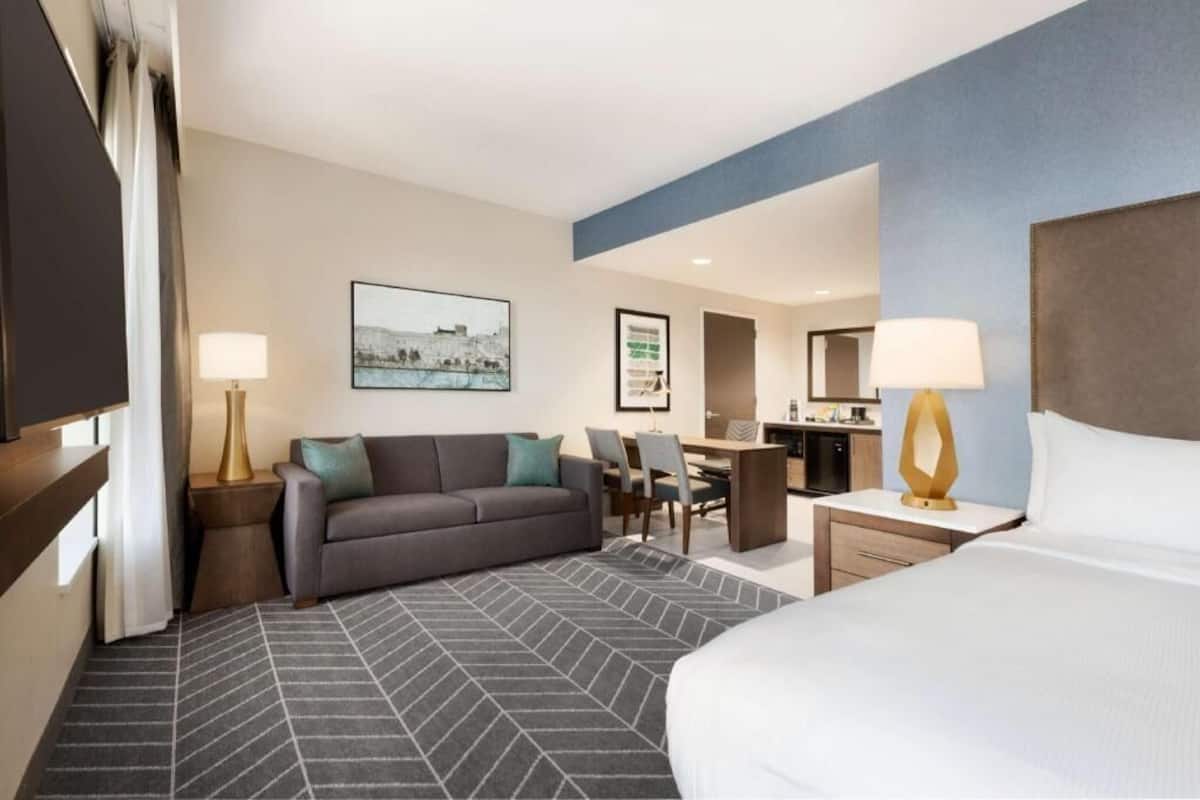 Ein Hotelzimmer mit Bett, einer Couch, einem Schreibtisch und einem Sessel.