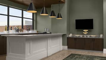 A modern kitchen with a large island, pendant lighting, and a flat-screen TV mounted on the wall.