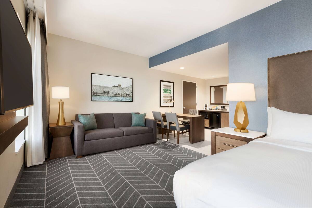 Ein Hotelzimmer mit Bett, Sofa, Schreibtisch und Essbereich.